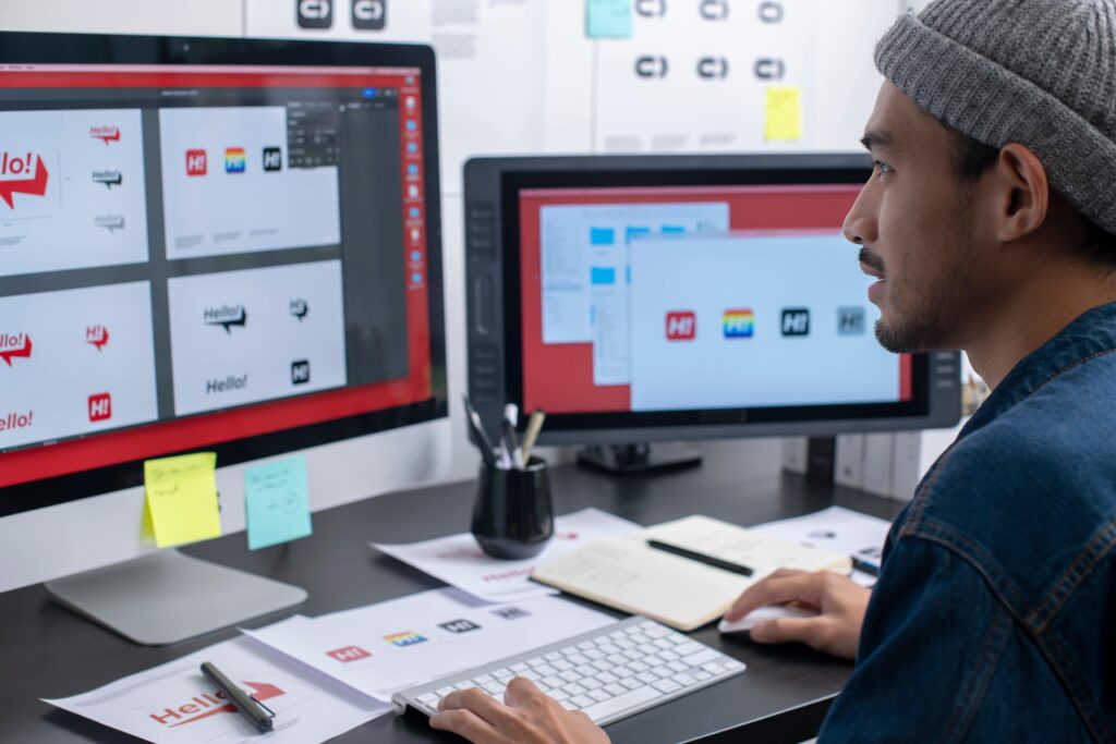 Hispanic male sitting at desk while looking at computer designing a logo
